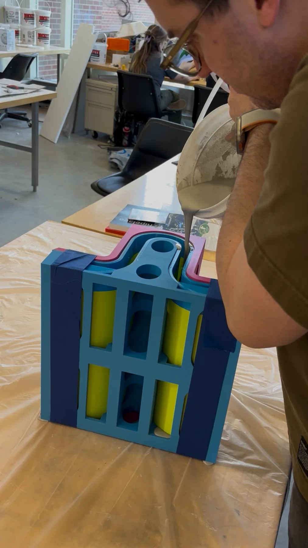 Concrete being poured into the 3D-printed Module 3 tray mold, its layered parts held tight with clamps.